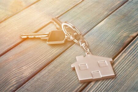 Silver Home key with badge on wooden table