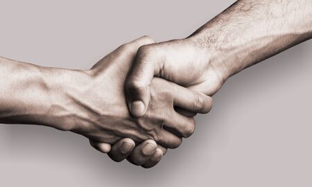 Hand holding another hand on gray background