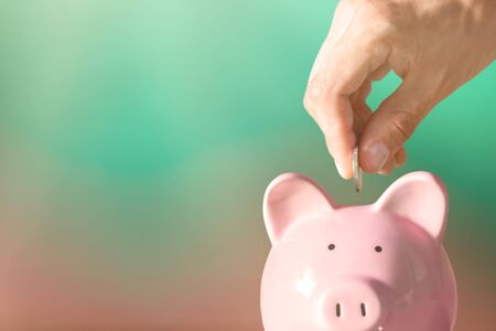 Hand putting coin to piggy bankの写真素材