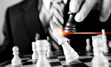 Business man playing chess - checkmate. Close-up chess pieces