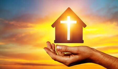 Hands with paper prayer house in the hands against the sky.の写真素材