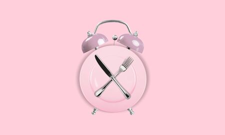 Alarm clock and plate with cutlery . Concept of intermittent fasting, lunchtime, diet and weight...
