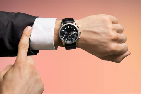 Businessman pointing at hand watch on grey wall background, close-upの写真素材