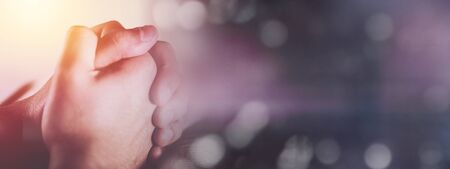 Hands of praying young man and Bible on a wooden desk backgroundの写真素材