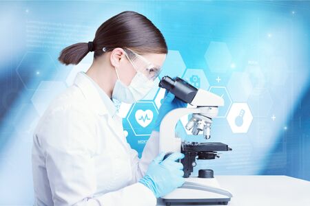 Young scientist looking through a microscope in a laboratory. Young scientist doing some research.の写真素材