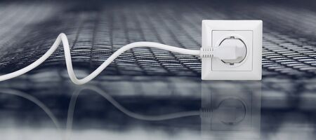White electrical plug in the electric socket on a wallの写真素材
