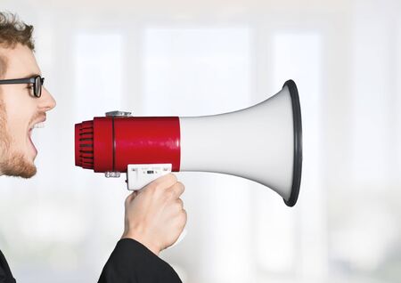Woman screams into megaphone in front of a blackboard