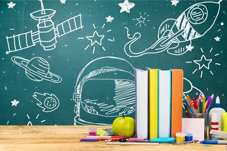 Back to school concept. rocket, earth globe and pencils in front of classroom blackboard