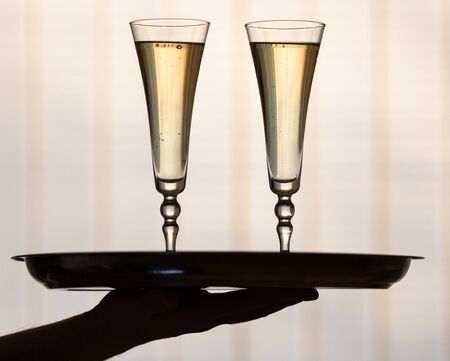 Hand Holding Two Champagne Glasses on the Tray