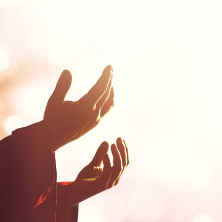 Silhouette rosary against cross in handの写真素材