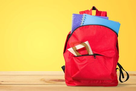 Backpack with different colorful stationery on table.の写真素材