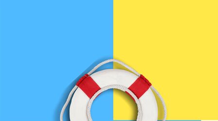 Lifebuoy on a yellow and blue background with blank space for text. Top view travel or vacation concept. Summer background. Flat lay photo, top viewの写真素材