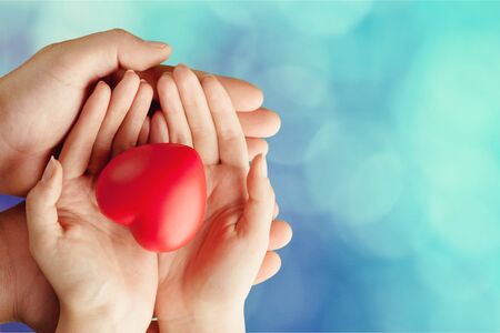 Adult and child hands holding red heartの写真素材