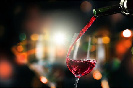 Pour red wine in wine glass on abstract backgroundの写真素材