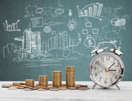 Golden coins stacks on wooden desk on diagrams background