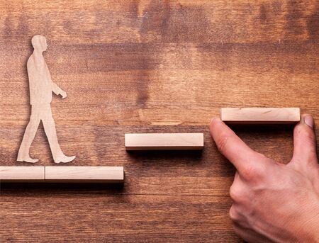 Success concept with wooden businessman climbing wooden