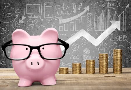 Piggy bank, calculator and coins on wooden tableの写真素材