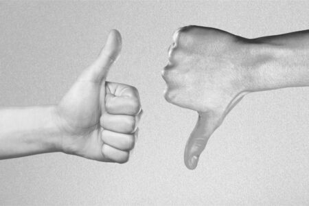 Two hands showing different gestures. Thumb up and thumb down, black and white