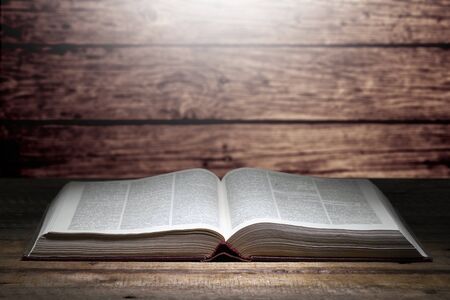 Opened old book on the old table. From the book light shines.の写真素材