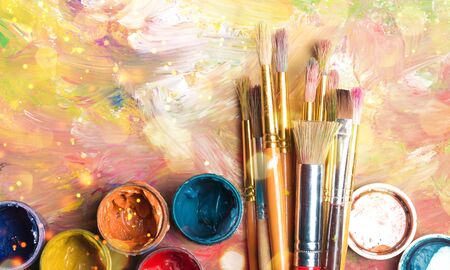 Artist paint brushes and paint cans of paint over bright watercolorの写真素材