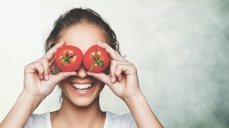 Beautiful laughing woman holding two ripe tomatoesの写真素材