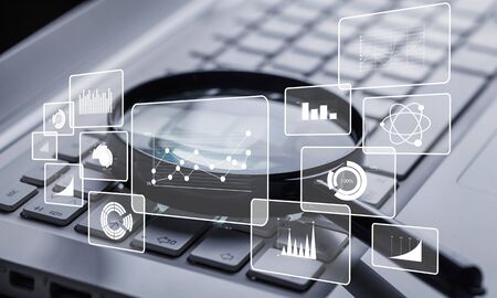 magnifying glass on laptop keyboard closeup with infographicsの写真素材