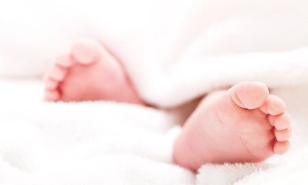 Mother holding newborn baby feet in hands. Mom taking care about infant child after taking bath. Parents childcare. Children healthcare and happy familyの写真素材