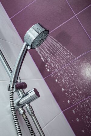 Shower Head with Water Stream on Purple Backgroundの写真素材