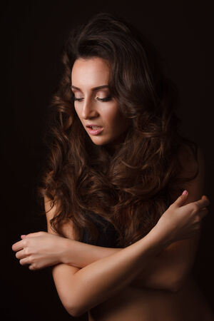 Sexy brunette girl in black lingerie on the black background. Sensual girl looking at the sideの写真素材