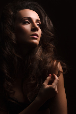 Sexy brunette girl in black lingerie on the black background. Sensual girl looking at the sideの写真素材