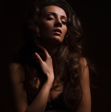 Sexy brunette girl in black lingerie on the black background. Sensual girl looking at cameraの写真素材
