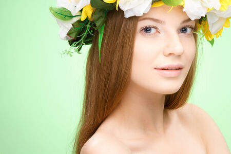 Young beauty woman portrait. Studio shot.  Girl with Flower wreath. Green background. Health Care, cosmetic concept. Blank for commercial advertisingの写真素材