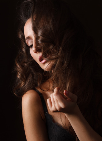 Sexy brunette girl in black lingerie on the black background. Sensual girl looking at the sideの写真素材