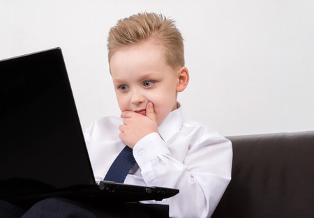 confused boy in suit looking at the computerの写真素材