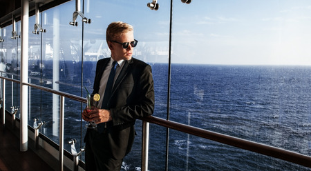 Luxury life. Portrait of the handsome and rich man. Shot from cruise liner. Sea on the background with copyspaceの写真素材