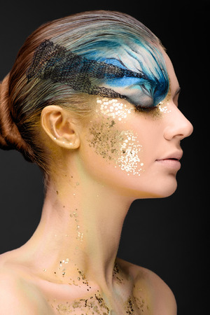 Young woman looking at the side with fantasy make up. Ususual face art studio shot. Copyspace. High resolutionの写真素材