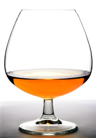 Glass with cognac on white background and wood base. Front view with copyspace. Close up shot. High resolutionの写真素材