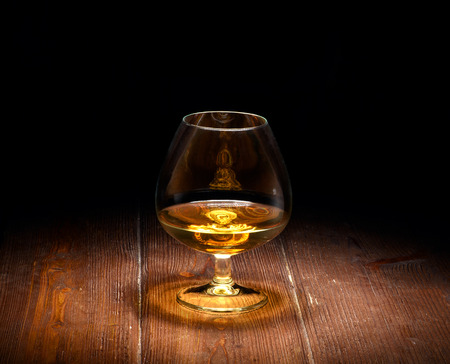 Luxury still life with glass of cognac, on a wood background. Front view with copyspace. Close up shot.の写真素材