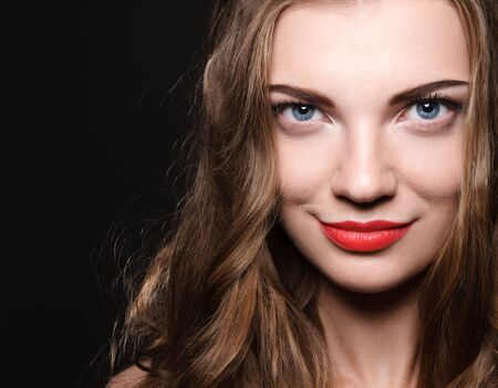 Beautiful caucasian young woman with red lips make up and curl hairs looking at camera. High resolution studio head shotの写真素材