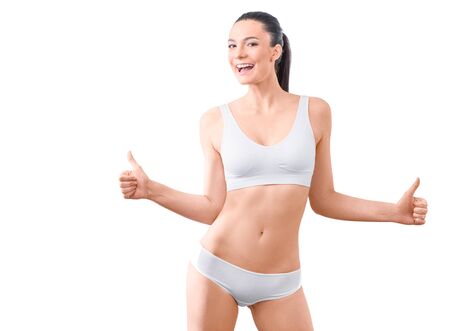 Woman with perfect slim body show thumbs up sign in underwear on the white background isolated. Healthcare, bodycare conceptの写真素材