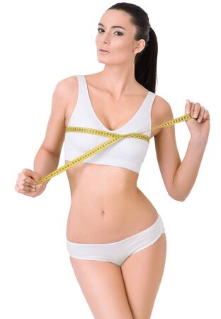 Slim woman in white underwear and measure around her body on white background isolated. Healthcare, diet, weight loss and body care concept.の写真素材