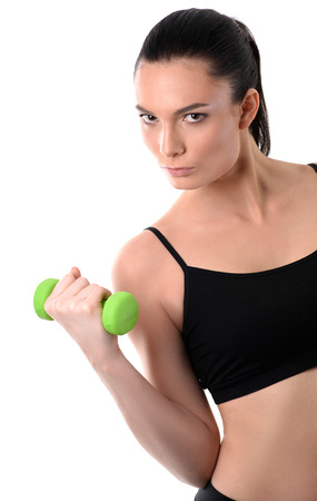 Portrait of fitness woman working out with green dumbbell looing at camera on isolated white backgroundの写真素材