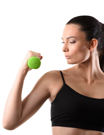 Fitness woman working out with green dumbbell looking at the arm on isolated white background. Fitness conceptの写真素材