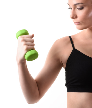 Fitness woman working out with green dumbbell looking at the arm on isolated white background. Fitness conceptの写真素材