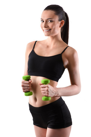 Portrait of happy fitness woman working out with green dumbbells looing at camera on isolated white backgroundの写真素材