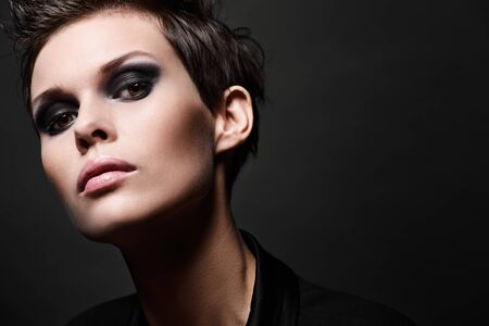 Fashion head shot of brunette woman with short hair cut on black background. Smokey eyes make upの写真素材