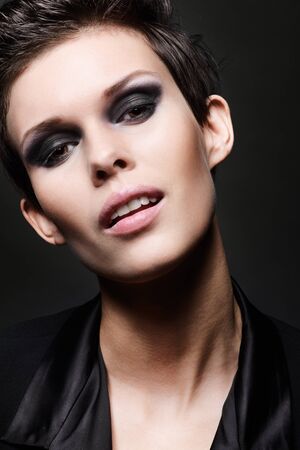 Fashion head shot of brunette woman with short hair cut on black background. Smokey eyes make upの写真素材