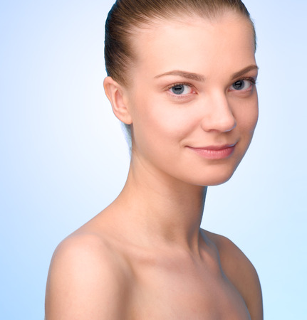 Portrait of beautiful young woman over light blue background looking at camera.  High resolutionの写真素材