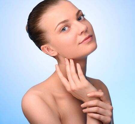 Beautiful woman face looking at camera over blue background. High resolution headshotの写真素材