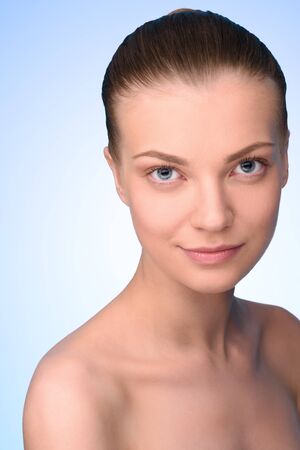 Portrait of beautiful young woman over light blue background looking at camera.  High resolutionの写真素材
